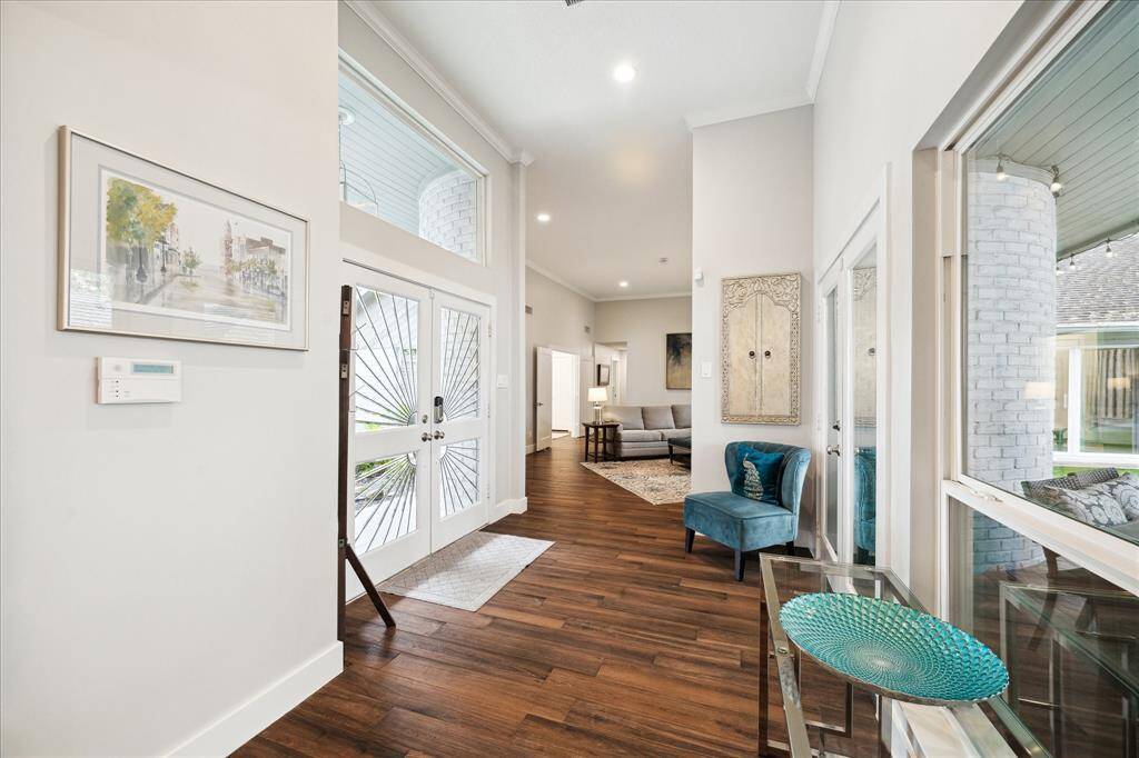 The spacious entryway with serene views of the covered patio and lush backyard. Straight ahead is the living room leading to bedrooms, each space effortlessly connected by the rich wood-look tile flooring.