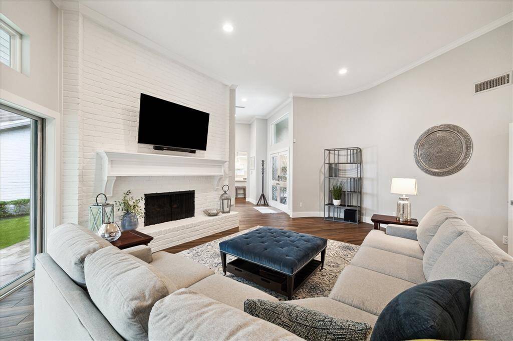 Bright and airy, this living room features rich wood-look tile and a grand white-brick fireplace under recessed lighting. Floor-to-ceiling sliding glass doors flood the space with natural light and open seamlessly to the covered patio and AstroTurf backyard.