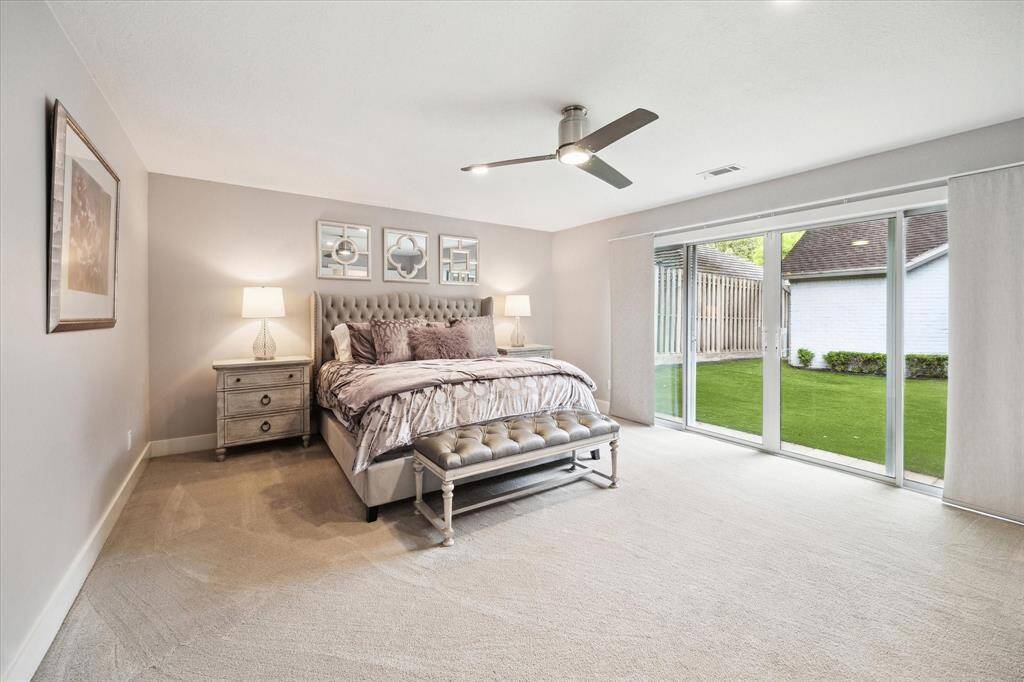 Past the living room, you'll find both the primary and secondary bedrooms. The primary bedroom is a peaceful retreat, filled with natural light from expansive glass windows and sliding doors that offer direct access to the backyard.