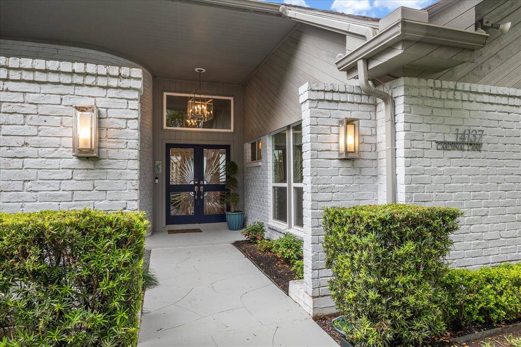 The inviting front entry, thoughtfully set back from the street, offers a sense of seclusion while welcoming you with warmth and charm. Step into style through a striking pair of double front doors, inset with custom-etched glass panels that form a radiant sunburst design. These artful doors make a bold statement while bathing the entryway in soft natural light.