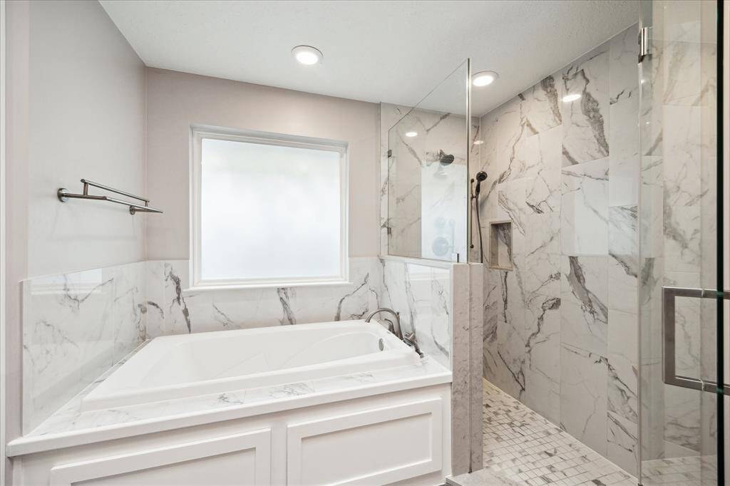 Recently remodeled, this spa-inspired primary bathroom features a luxurious jetted tub, a large walk-in shower, and updated PEX piping throughout for added peace of mind.