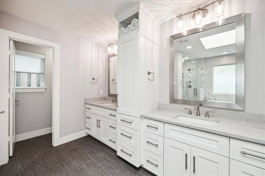 A spacious vanity offers plenty of storage, while a large walk-in shower with frameless glass adds a luxurious touch.