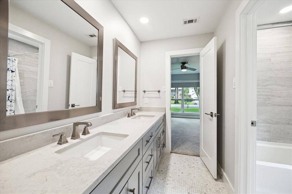 Beautifully updated, this bathroom features a custom vanity with quartz countertop, dual sinks and a modern layout, perfectly designed for convenience and comfort. Shared by the secondary bedrooms.