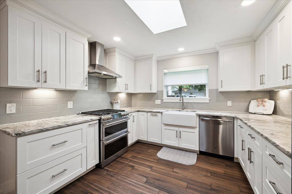 The kitchen is spacious and thoughtfully designed. A large apron-front sink adds charm and functionality. Custom cabinetry with large drawers and stainless steel appliances including the gas range with double oven.