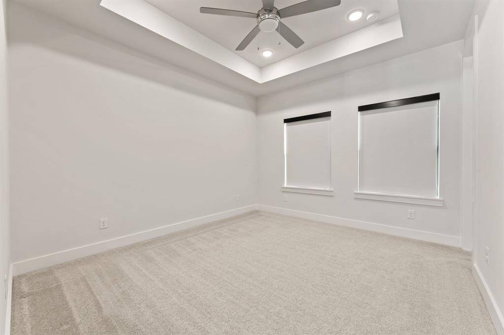 The additional bedroom located on the second floor features a tray ceiling with recessed lighting, a ceiling fan, and an en-suite bathroom. Two large windows provide natural light, equipped with sleek black-out shades.