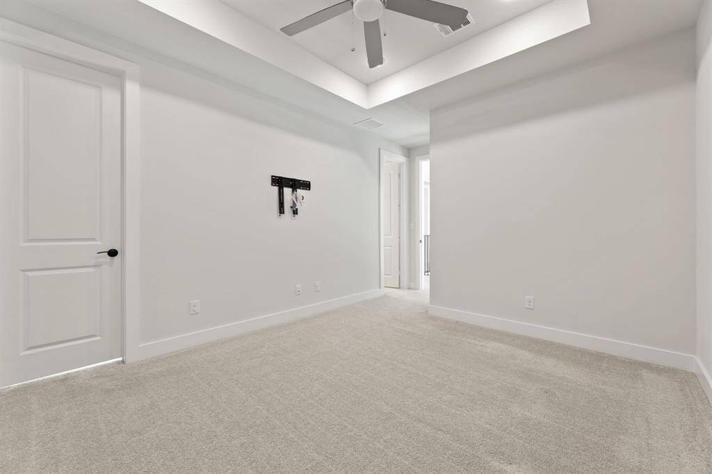 The additional bedroom located on the second floor features a tray ceiling with recessed lighting, a ceiling fan, and an en-suite bathroom. Two large windows provide natural light, equipped with sleek black-out shades.