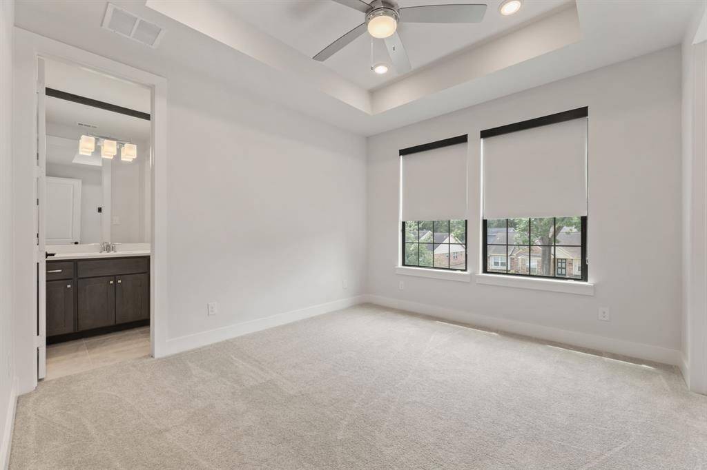 The additional bedroom located on the second floor features a tray ceiling with recessed lighting, a ceiling fan, and an en-suite bathroom. Two large windows provide natural light, equipped with sleek black-out shades.