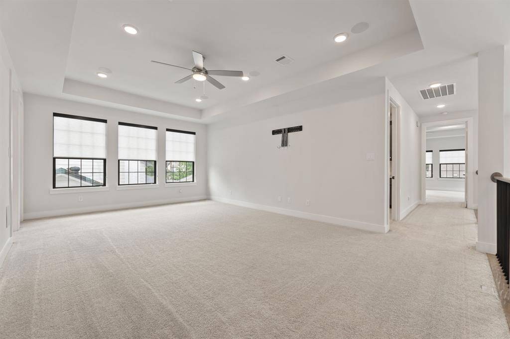 Spacious upstairs game room perfect for entertainment and relaxation. Features three large windows for natural lighting, a modern railing overlooking the lower level and connects to adjacent rooms, offering versatile living space.