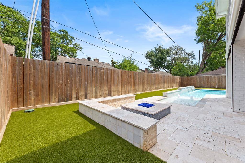Enjoy a stunning backyard oasis featuring a sparkling pool with heating and cooling functionality and lush artificial turf, perfect for relaxation and entertaining.