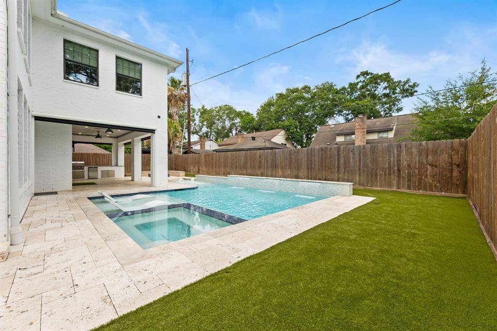 Enjoy a stunning backyard oasis featuring a sparkling pool with heating and cooling functionality and lush artificial turf, perfect for relaxation and entertaining.