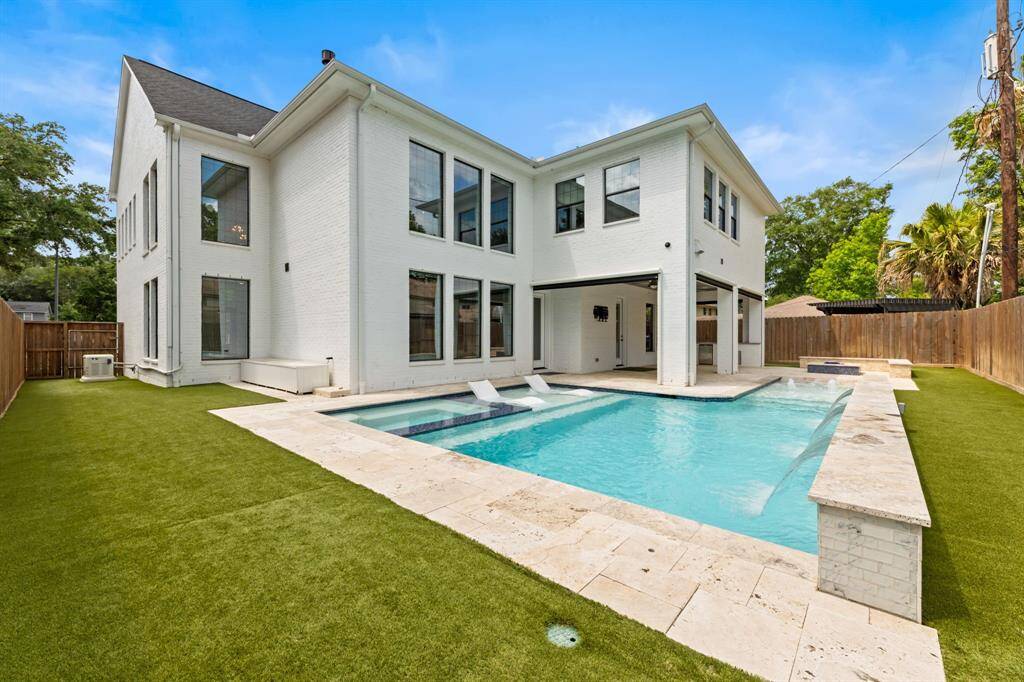 Enjoy a stunning backyard oasis featuring a sparkling pool with heating and cooling functionality and lush artificial turf, perfect for relaxation and entertaining.