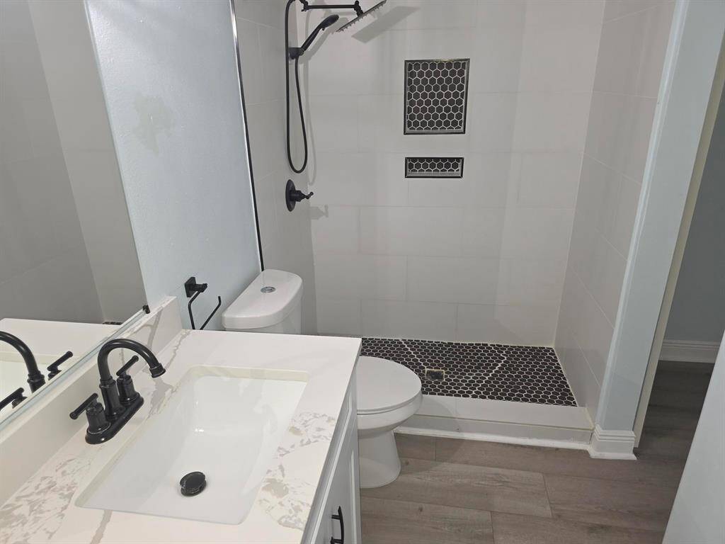 This modern bathroom features a sleek shower with black hexagonal tiles and built-in shelving, a stylish vanity with a marble countertop, and matte black fixtures for a contemporary look.