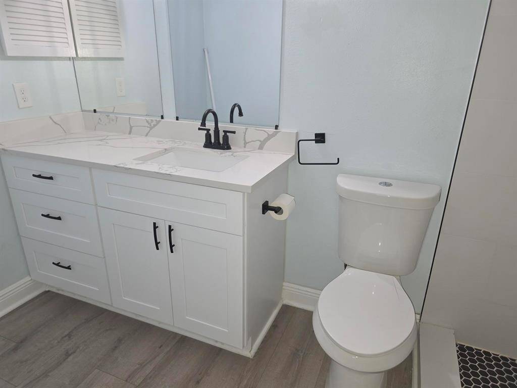 This bathroom features a modern design with a light-colored vanity, sleek black fixtures, and a spacious counter. The flooring complements the overall contemporary aesthetic.