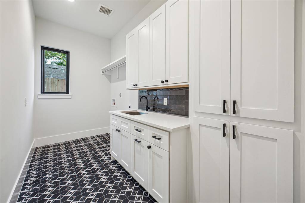 The well-equipped laundry room has a built-in trash drawer and passthrough to primary closet.