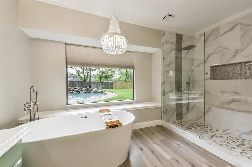 Situated across from the luxurious freestanding soaking tub is the oversized walk-in shower with elegant floor-to-ceiling tile, a rainfall showerhead, and a built-in niche for convenience. This beautifully designed space offers both relaxation and style. A true highlight of the primary suite, it's ideal for unwinding after a long day.