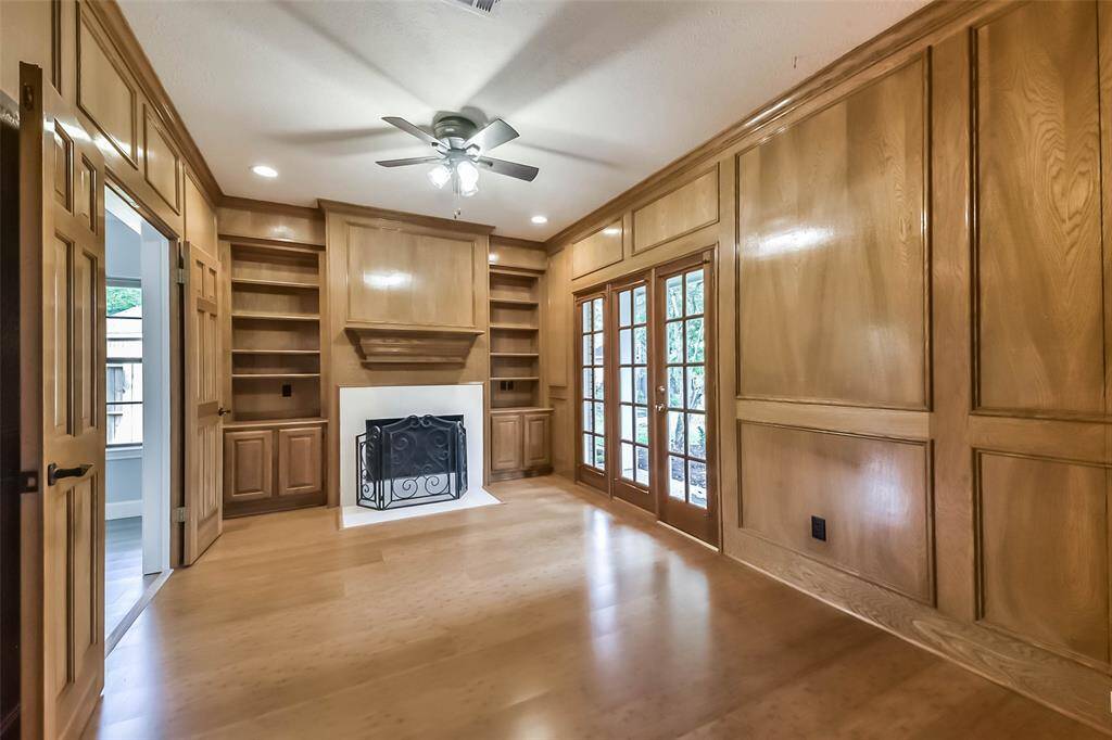 This warm and inviting home office or study features rich wood paneling, built-in shelving, and a cozy fireplace, creating a refined and functional workspace. Double French doors from the foyer offer an elegant entry, while a private set of double doors provides direct access to the primary suite. Ample natural light and classic details make this space ideal for working from home or relaxing with a good book. It's the perfect blend of privacy, comfort, and timeless charm.