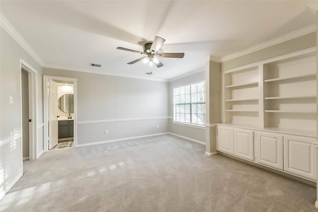 Located on the second floor, this versatile game room offers the perfect space for entertaining or relaxing. Built-in shelving and cabinetry provide ample storage for games, books, or media equipment. A large window brings in natural light, while the neutral tones and crown molding add a polished touch. With direct access to a full bath, this space is ideal for hosting guests or enjoying movie and game nights with the family.