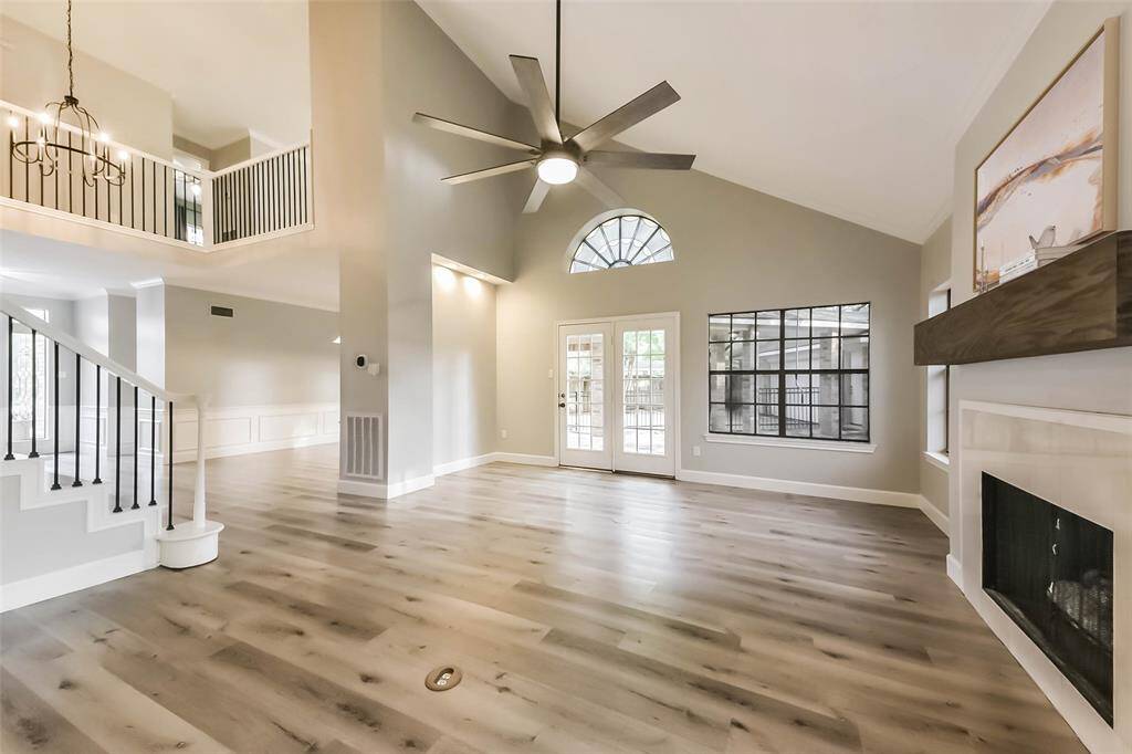 This beautiful open-concept living area boasts soaring vaulted ceilings and an abundance of natural light. Modern light fixtures enhance the space's contemporary charm. The seamless flow from the living room with its cozy fireplace to the dining area, and access to the back patio makes it perfect for entertaining. Neutral tones and large windows create a bright and inviting atmosphere. Virtually staged.