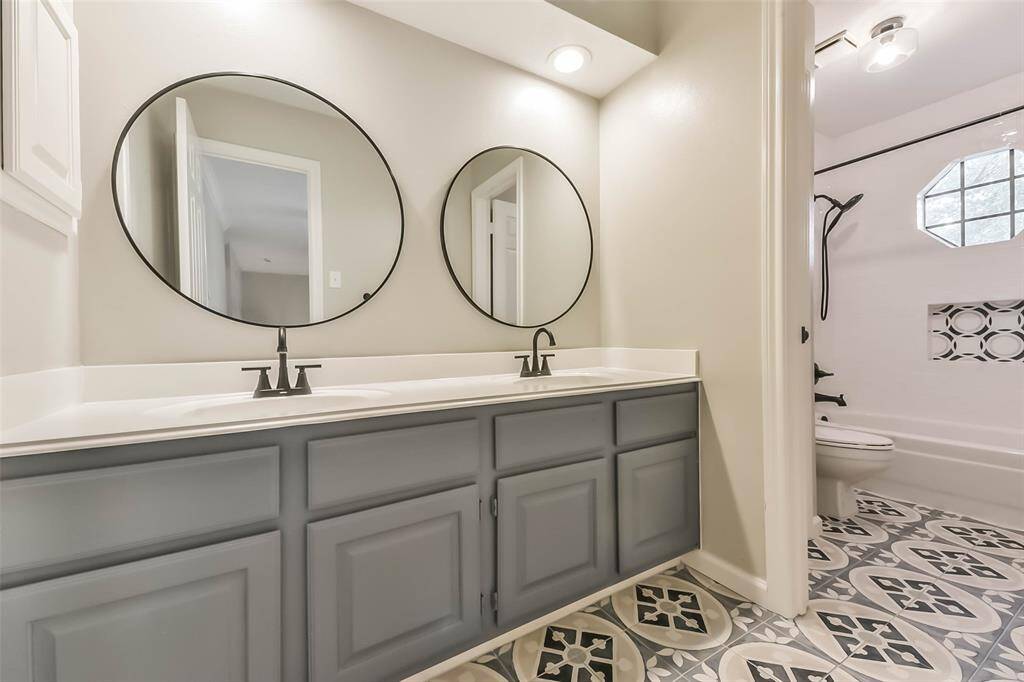 This stylish full bathroom, located upstairs, features a spacious double sink vanity with modern fixtures and ample storage. Decorative tile flooring adds a unique and elegant touch. The walk-in tub/shower includes a window that brings in natural light while maintaining privacy. Perfectly designed for shared use, this bathroom combines function with fresh, contemporary finishes.