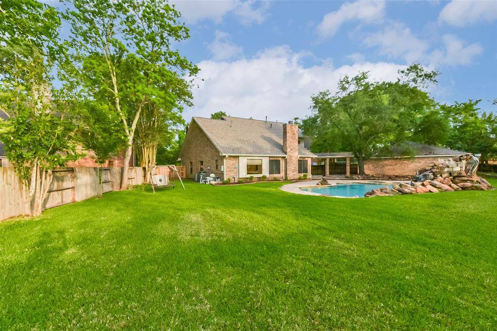 This expansive backyard is the perfect space for outdoor living and entertaining, featuring a sparkling pool with a rock waterfall feature. The large grassy area offers plenty of room for play, gardening, and pets. Mature trees and a fully fenced yard provide both shade and privacy. Enjoy the ideal blend of relaxation and recreation right at home.