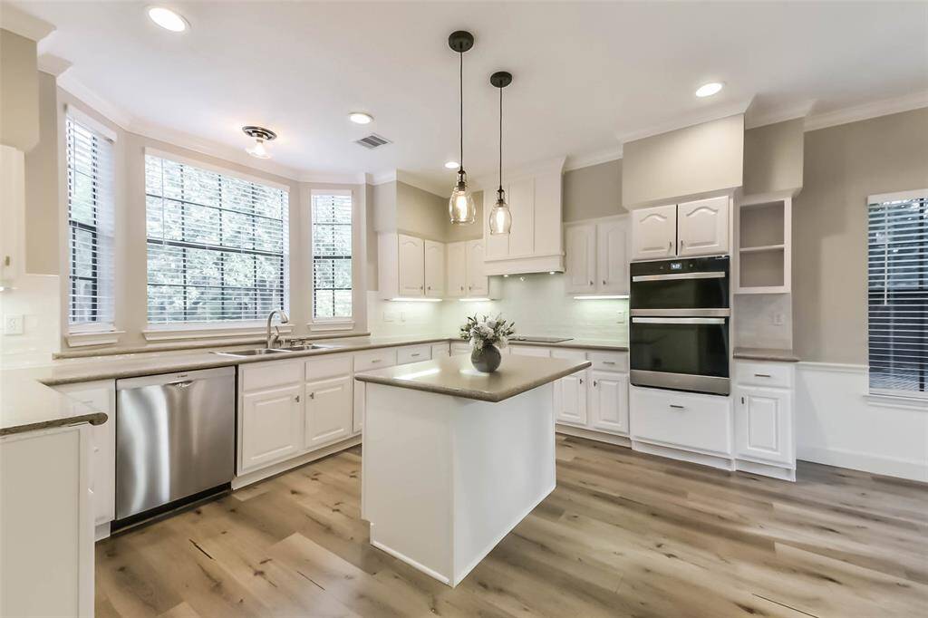 This bright and spacious kitchen features crisp white cabinetry, sleek granite countertops, and stainless steel appliances. A large center island offers additional prep space and is accented by stylish pendant lighting. The bay windows provide ample natural light, creating an inviting atmosphere for cooking and entertaining. With built-in oven and microwave, under cabinet lighting, and plenty of storage, this kitchen is as functional as it is beautiful. Virtually staged.