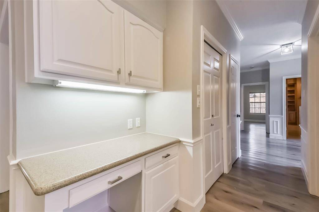 This built-in command center, located just off the kitchen, is the perfect space to manage household tasks or work from home. Featuring upper and lower cabinetry for added storage and a spacious countertop workspace, it keeps everything organized and within reach. Under-cabinet lighting adds a bright, functional touch for productivity. Conveniently positioned near main living areas, it blends efficiency with everyday ease.