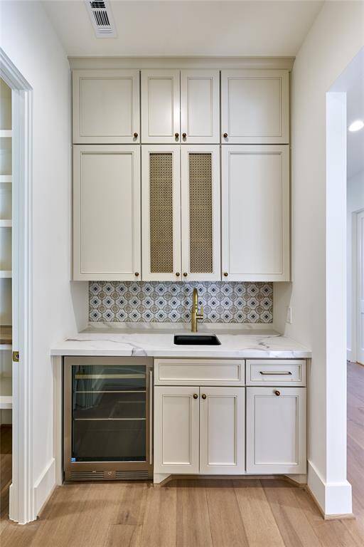 Showcasing a stylish wet bar with decorative tile backsplash, and a built-in wine cooler.