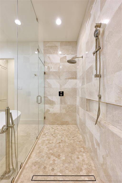 Spacious walk-in shower adorned with limestone and marble mosaic tile, creating a luxurious and visually striking design.