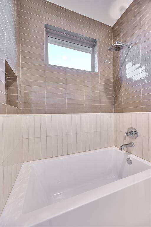 The Jack and Jill bathroom features a stylish shower/tub combo, with artisan oyster ceramic tile and rich chestnut ceramic tile adorning the shower.