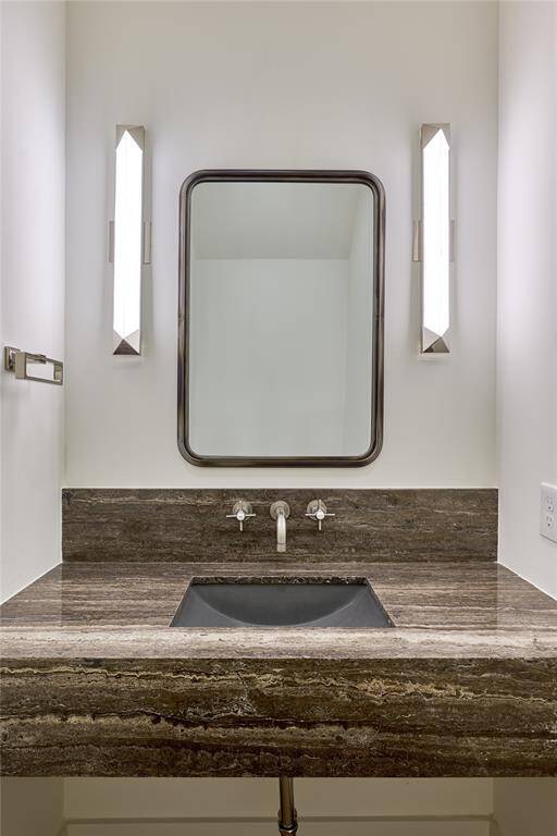 Sophisticated power room featuring a dark stone countertop and modern wall sconces.
