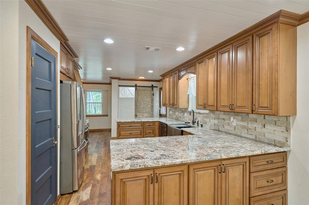 Granite counters and large farm sink showed off by travertine backsplash.