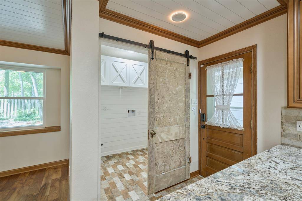 Back door from covered walkway from garage and utility room with barn door.