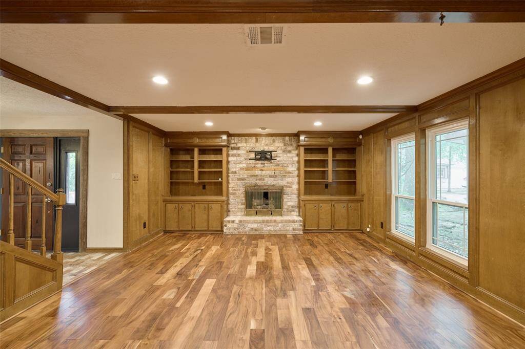 Large family room with decorative only fireplace flanked by built ins including a wet bar!