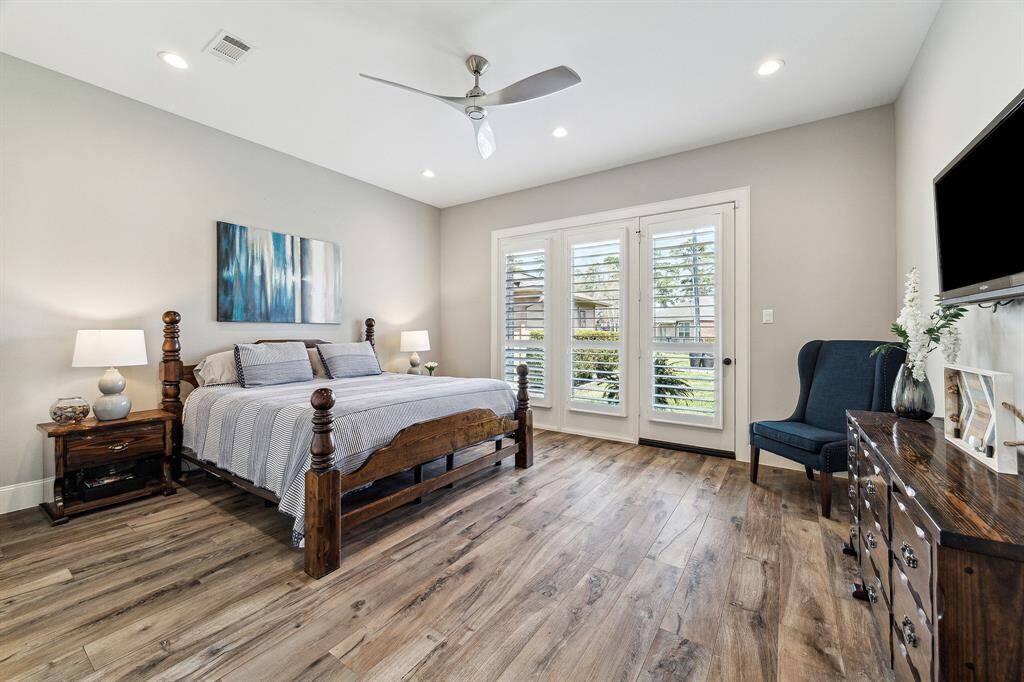 The spacious primary bedroom on the first floor offers stunning views of the backyard and features a door that opens directly to the outdoor space. It also boasts tile flooring.