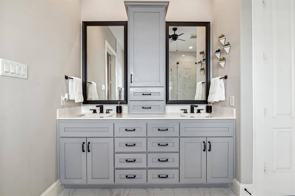 The primary bath features double sinks with ample storage, quartz countertops, and stylish black fixtures.