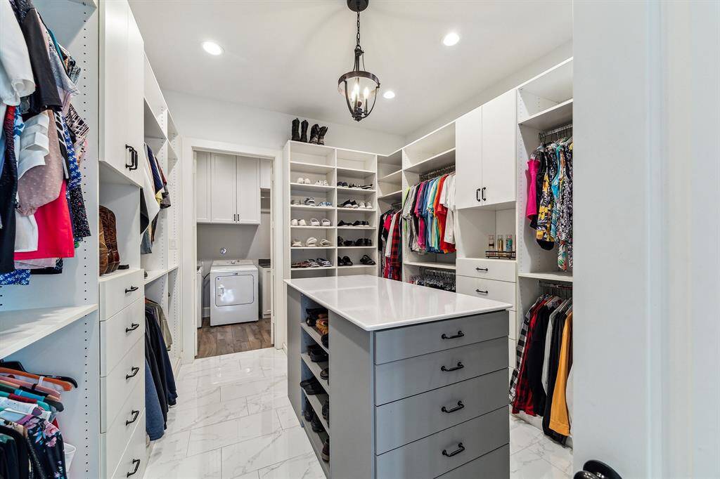 Large primary closet with island and ample storage. A double French door opens onto the utility room for convenience.
