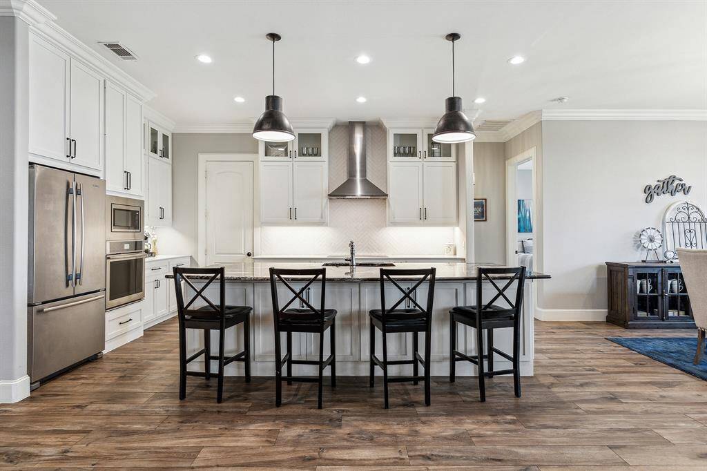 Modern kitchen has large plus sized Granite countertops with abundant storage, two pendant lights, Jennair appliances and two electric ovens.