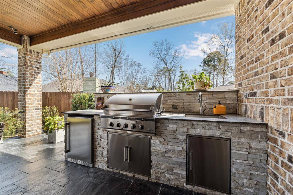 Outdoor kitchen with DCS gas grill, 24" Zephyr beverage center and bar sink.
