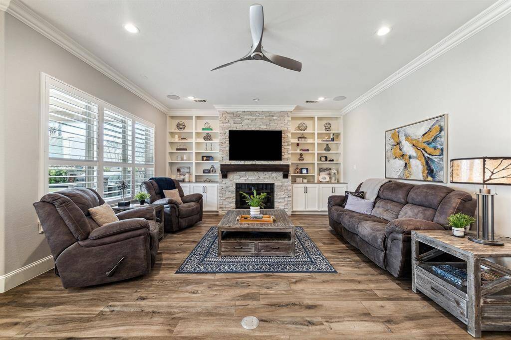 Another view of the living room with built-in shelves and and a stunning floor-to-ceiling stone fireplace with mantle.