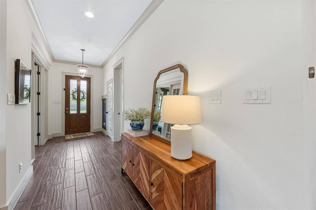 Step inside to discover wood-look tile flooring complemented by bright white walls, natural light, and elegant crown molding.