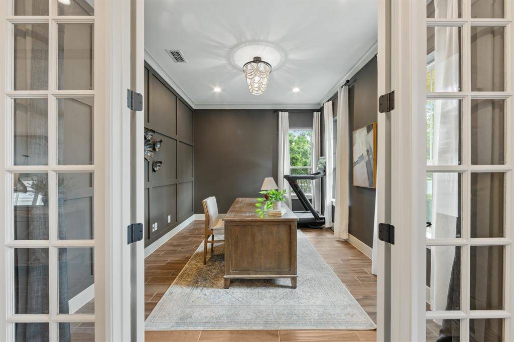 Positioned to the right of the entrance, this striking workspace features dramatic dark grey walls that create a bold, focused atmosphere, accented by a beautiful white chandelier for elegant illumination.