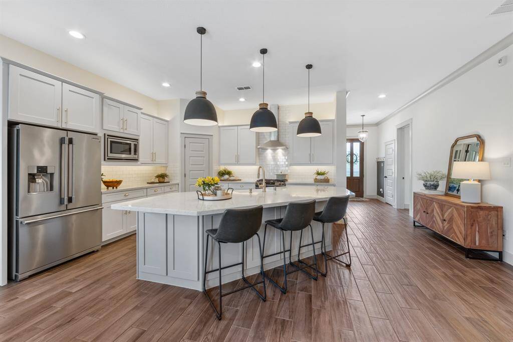 The seamless open-plan kitchen flows directly from the hallway, anchored by crisp white cabinets and a spacious island with a built-in sink.