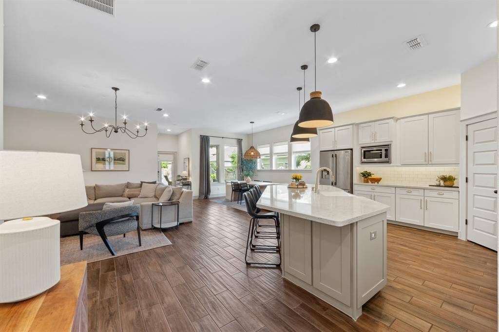 Clean lines and an uncluttered design emphasize the airy layout, while the oversized island serves as both a functional workspace and a natural divider between cooking and living areas.