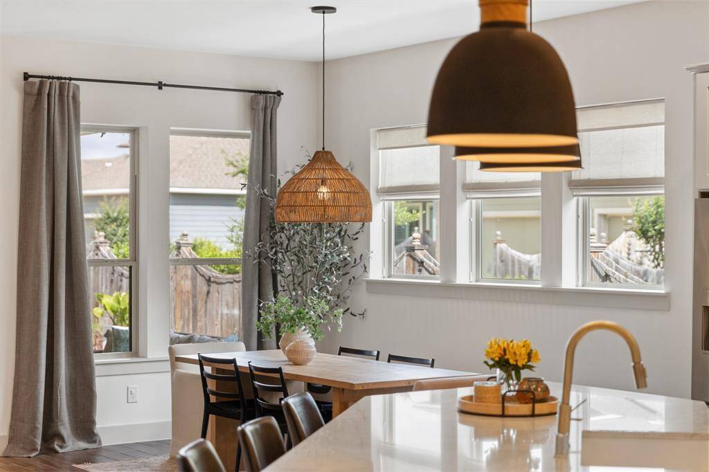 The breakfast nook features a light brown wood table with a threaded pendant fixture overhead, casting warm illumination over casual meals.
