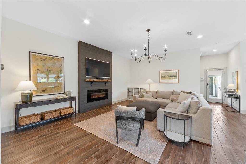 The family room features a minimalistic fireplace and a clean-lined silhouette chandelier that serves as a striking focal point.
