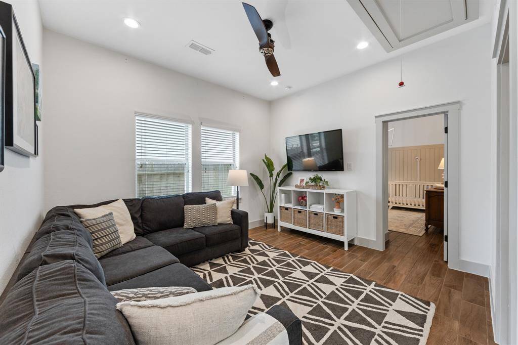 The living room features a dark wood-like ceiling fan and seamlessly connects to the game room, both enjoying ample natural light from abundant windows.