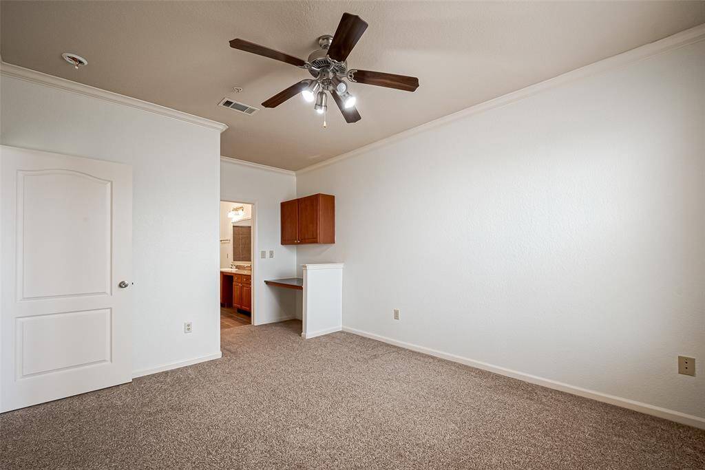 Bedroom has a doorway leading to a bathroom, visible cabinetry, and a small built-in desk area, offering functionality and comfort.