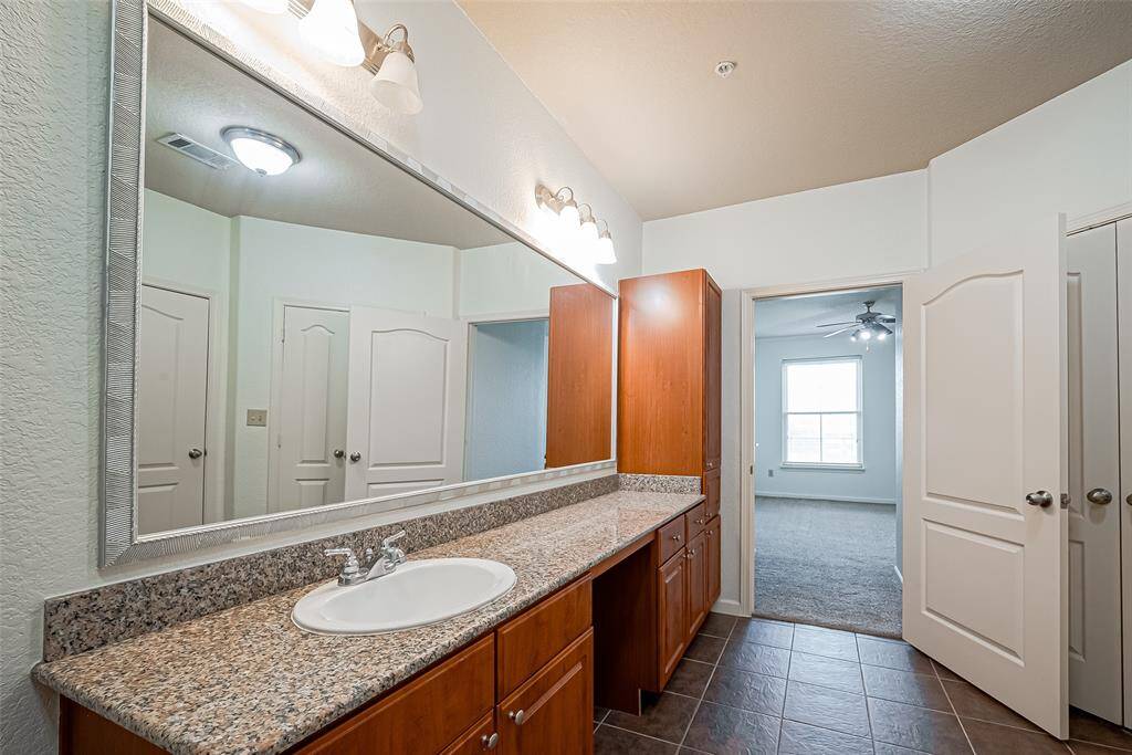 Enjoy this long granite countertop and single sink, ample wood cabinetry, and a large mirror.