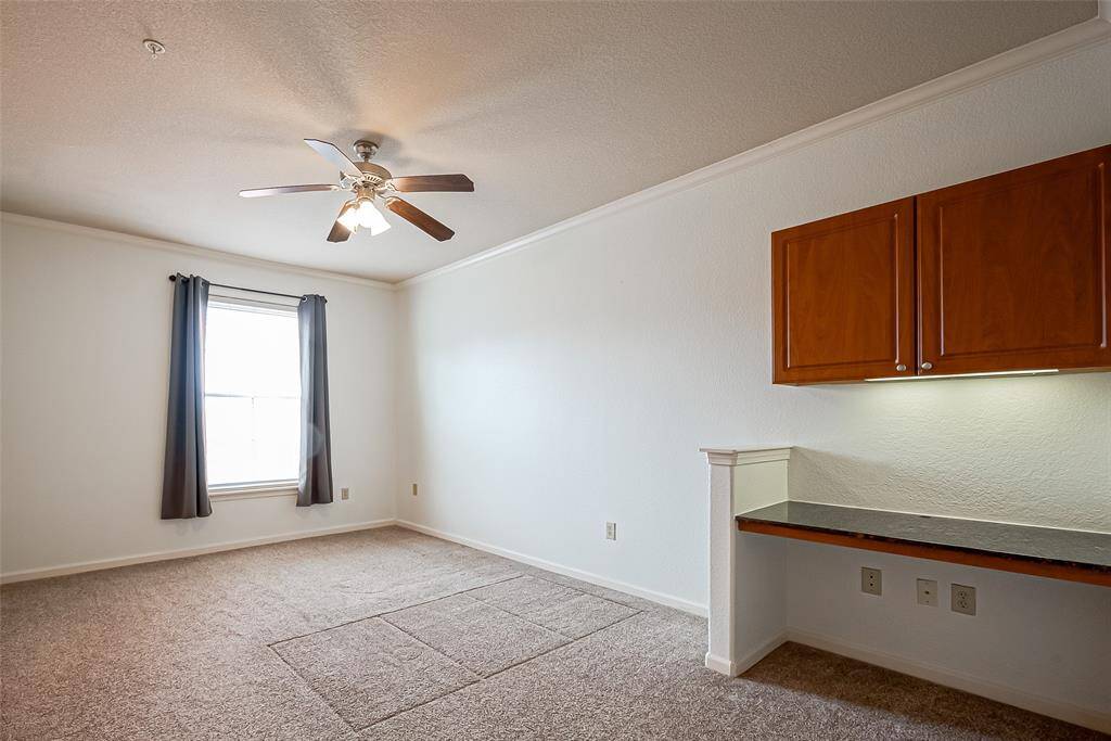This space includes built-in wooden cabinets and a small desk area, ideal for a home office or study nook.