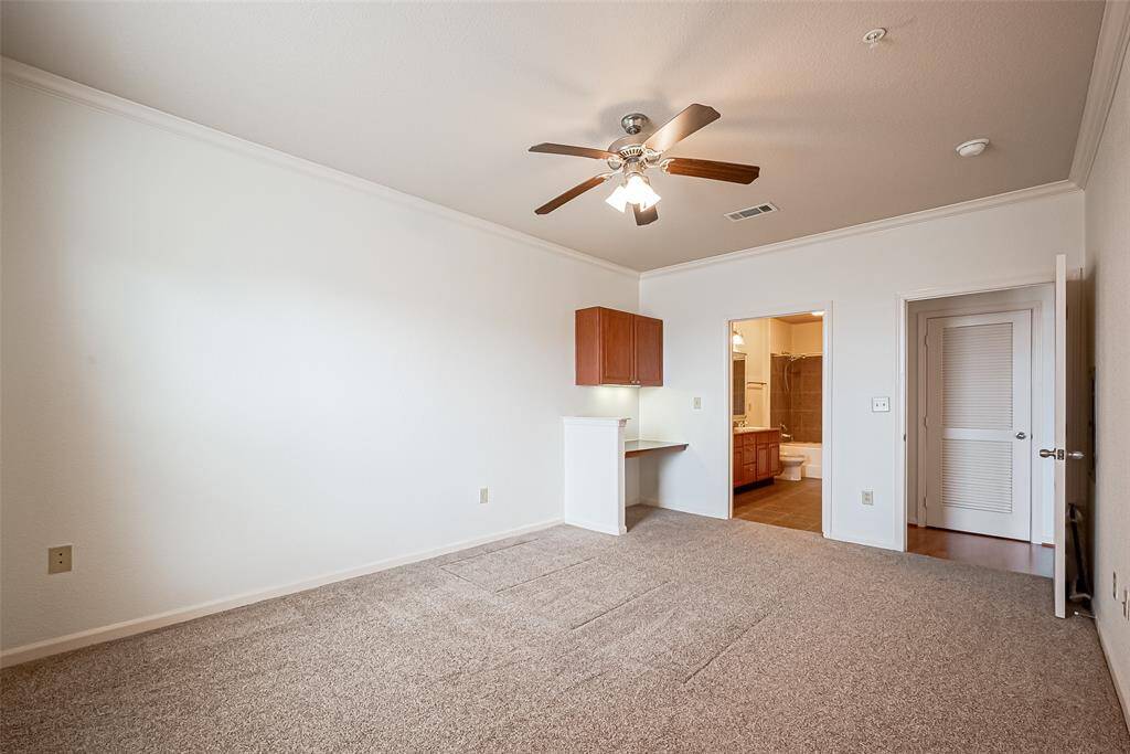 It includes a small built-in desk area and has an en-suite bathroom with modern fixtures. The room is well-lit and offers ample space for furnishings.